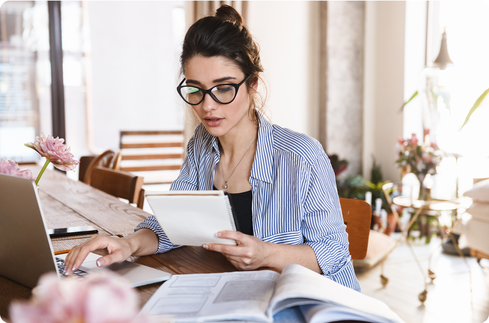 Kobieta w okularach pracująca przy laptopie z dokumentami
